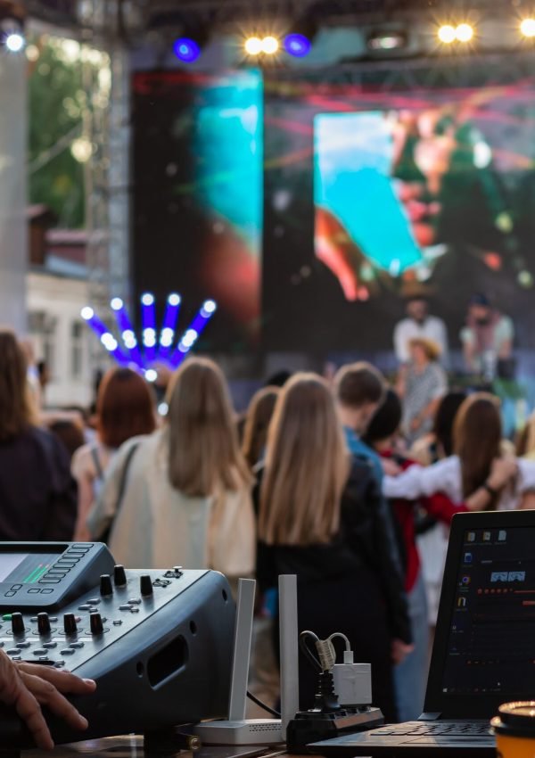 Dj mixing, laptop outdoors at party festival with crowd of people in background. Fun, summer, youth, nightlife, music and entertainment concept. low light. selective focus. professional DJ music mixer